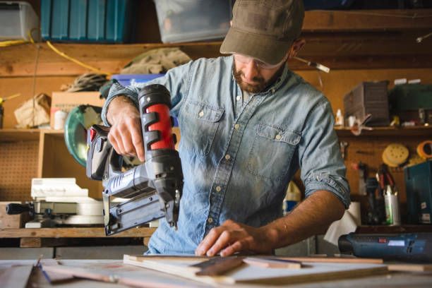 artist using nail gun on wooden art at workshop - nails art stock pictures, royalty-free photos & images