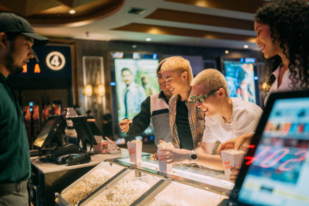 asian bartender serving a gay couple in front bar counter for popcorn before movie show time at movie theater cinema. - junk food stock pictures, royalty-free photos & images