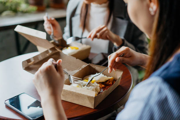 asian businesswomen having take away food during lunch break - junk food stock pictures, royalty-free photos & images