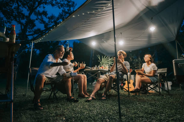 asian chinese family with 2 teenager offspring enjoying dinner at camping tent late evening - home decoration stock pictures, royalty-free photos & images