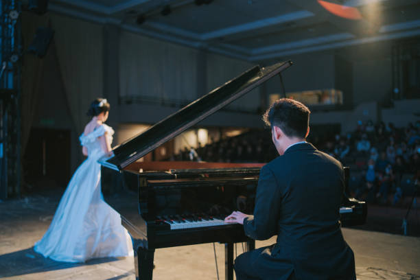 asian chinese pianist playing grand piano with female opera singer performing solo on stage - concert stock pictures, royalty-free photos & images