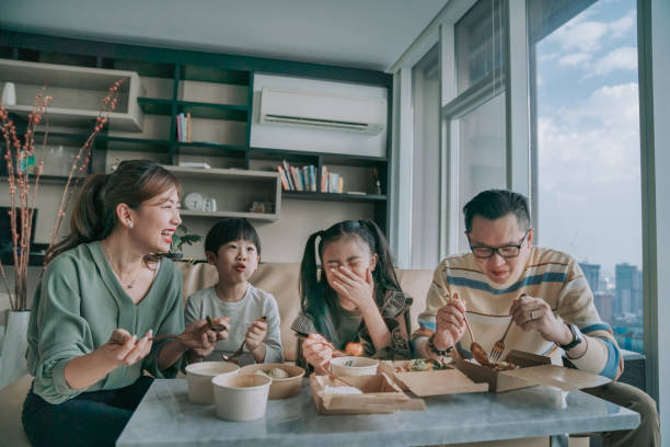 asian chinese young family enjoying take out food in front of tv in living room during weekend - junk food stock pictures, royalty-free photos & images