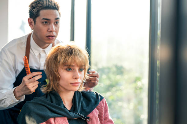 asian hairdresser owner is giving advice about hairstyle to his customer at hair salon. - hairstyle stock pictures, royalty-free photos & images