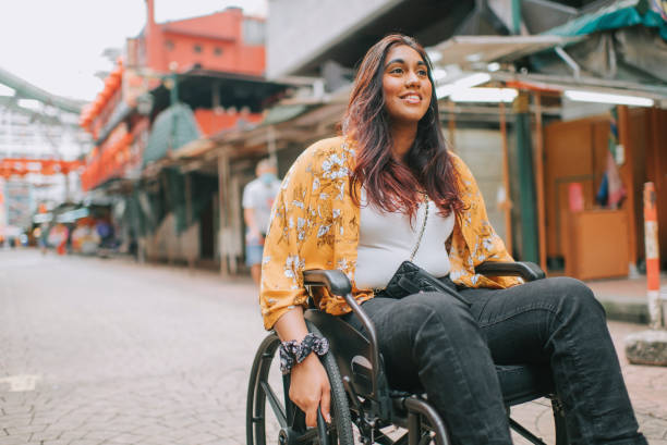 asian indian beautiful woman with disability using wheelchair exploring downtown district in kuala lumpur - travel stock pictures, royalty-free photos & images