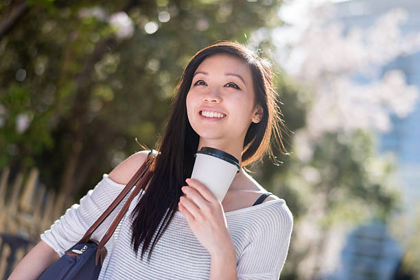 asian woman drinking coffee on the go - junk food stock pictures, royalty-free photos & images