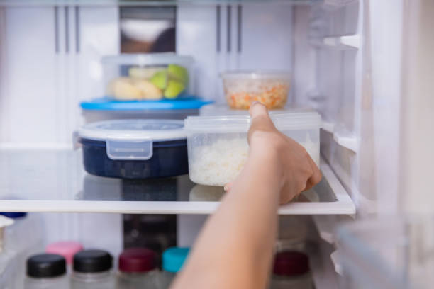 asian woman stored leftovers food in plastic container put into refrigerator. - food stock pictures, royalty-free photos & images