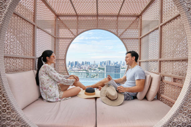 asiatisches paar entspannt sich und lacht in einer cabana am hotelpool - travel stock-fotos und bilder