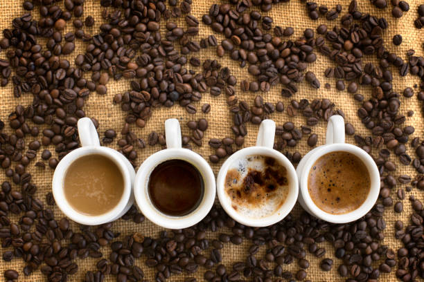 assorted coffee drinks in cups on coffee beans background - coffee stockfoto's en -beelden