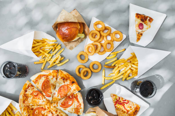assorted take out food such as pizza, french fries, onion rings, burger and cola. - junk food stock pictures, royalty-free photos & images