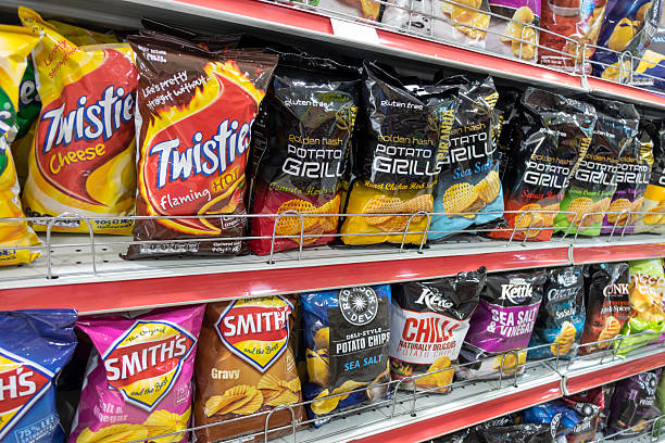 Australia, Sydney, Central Business District CBD convenience store shelves food junk snack potato chips bags competing brands packaging sale retail...