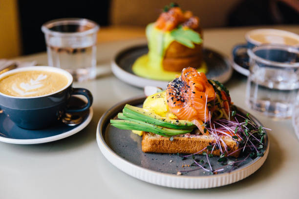 avocado toast with salmon and poached egg served for breakfast at a cafe - food stock pictures, royalty-free photos & images