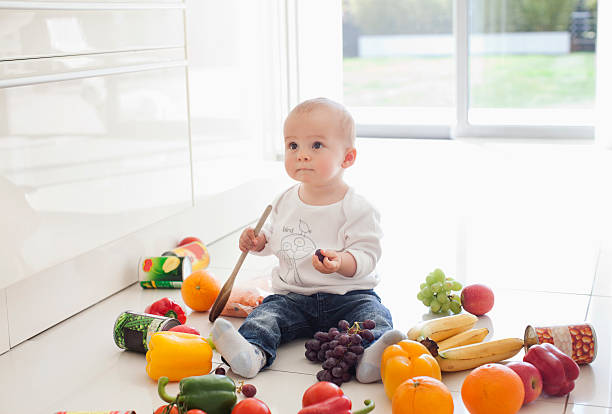 baby making mess on floor with food - food stockfoto's en -beelden