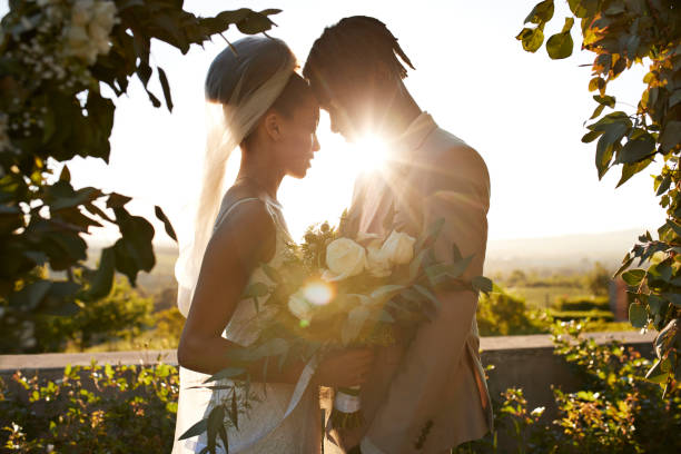 back lit bride and groom touching foreheads at wedding altar - garden decoration stockfoto's en -beelden