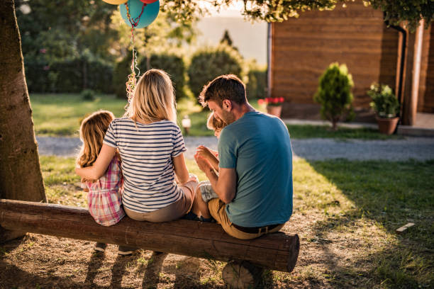 back view of relaxed family on a bench in the backyard. - garden decoration stock pictures, royalty-free photos & images