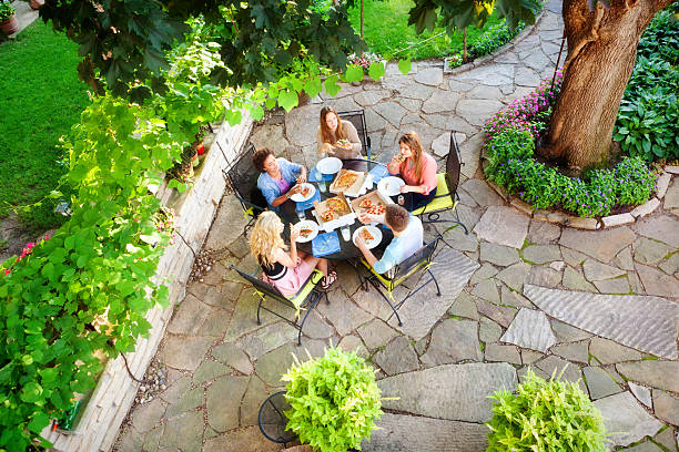 backyard patio, landscaping and garden with teenagers enjoying pizza - junk food stock pictures, royalty-free photos & images