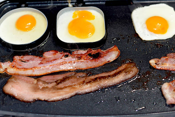 bacon and eggs on griddle - junk food stock pictures, royalty-free photos & images