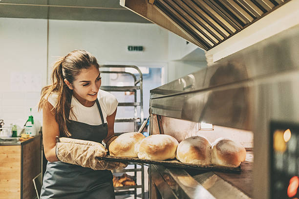 baker pulling a tray with hot bread - food stockfoto's en -beelden