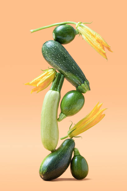 balance with green zucchini vegetables on beige background. healthy food and life balance concept. - food stock pictures, royalty-free photos & images