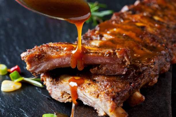 barbecue sauce dripping on marinated and grilled spare ribs - food stockfoto's en -beelden