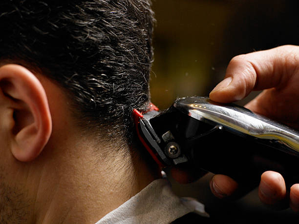 barber cutting man's hair, close-up of electric razor, side view - hairstyle stockfoto's en -beelden