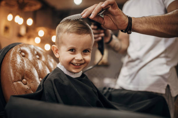 barbero secando el cabello del niño después de cortarle el pelo en la barbería - hairstyle fotografías e imágenes de stock