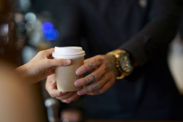 barista serving coffee in takeaway paper disposable cups to client in coffee shop - junk food stock pictures, royalty-free photos & images
