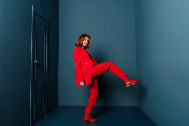 beautiful fashionable woman walking in a room with a door in a red suit indoors. concept - fashion stock-fotos und bilder
