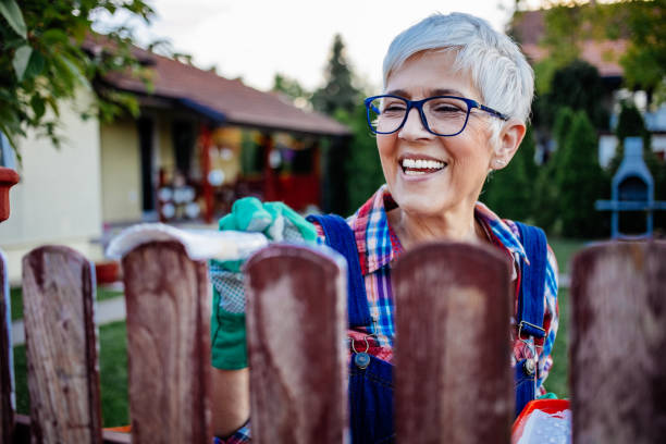 beautiful mature women painting fence - garden decoration stock pictures, royalty-free photos & images