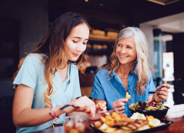 beautiful senior mother and daughter eating lunch together at restaurant - food stock pictures, royalty-free photos & images