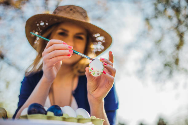beautiful woman decorating easter eggs in garden for holiday - garden decoration stock pictures, royalty-free photos & images