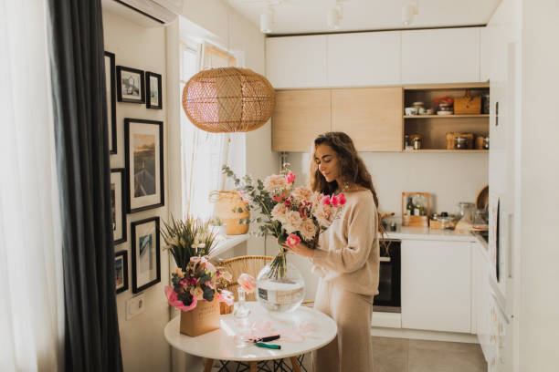 beautiful woman decorating house with flowers. - home decoration stock pictures, royalty-free photos & images