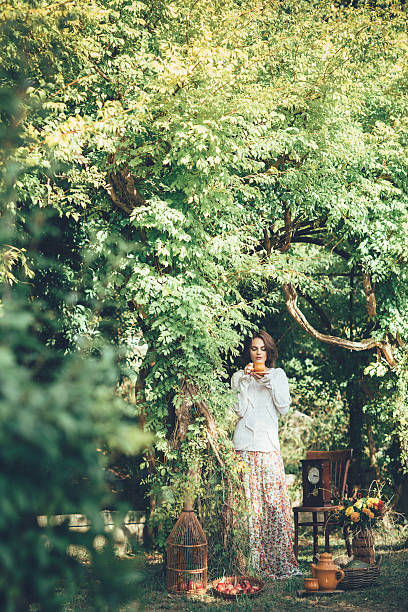 beautiful woman drinking tea in a magical park - garden decoration stock pictures, royalty-free photos & images