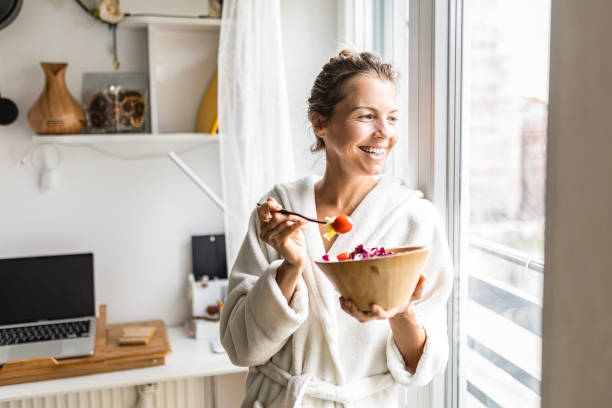beautiful woman eating healthy vegetable salad wearing bathrobe - food stock pictures, royalty-free photos & images