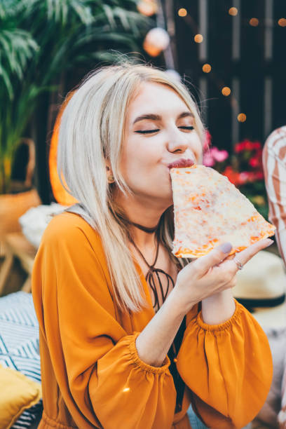 beautiful woman eating pizza. - junk food stock pictures, royalty-free photos & images