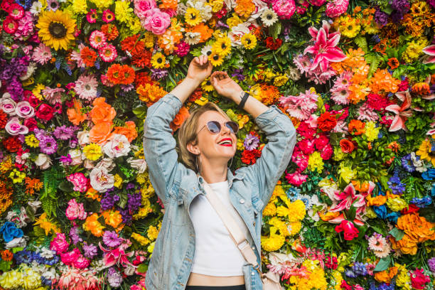 beautiful woman smiling in front of flower wall - garden decoration stock pictures, royalty-free photos & images