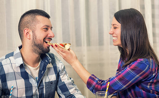 beautiful young couple eating pizza together - junk food stock pictures, royalty-free photos & images
