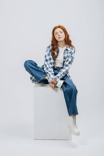 beautiful young model posing sitting in studio on cube white background casual new clothes catalog. fashion and trend concept - fashion stock pictures, royalty-free photos & images