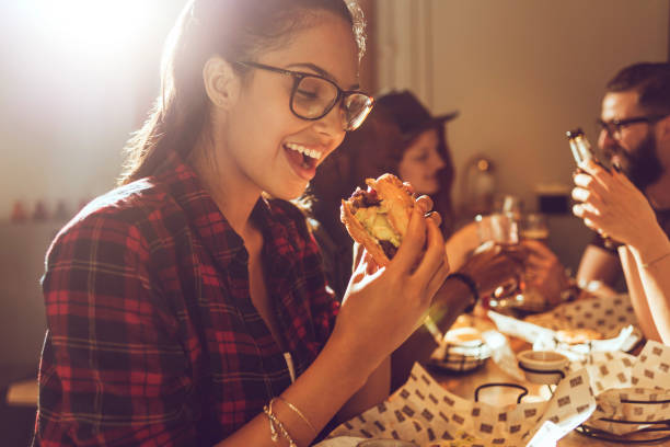beautiful young woman enjoying her burger - junk food stock pictures, royalty-free photos & images