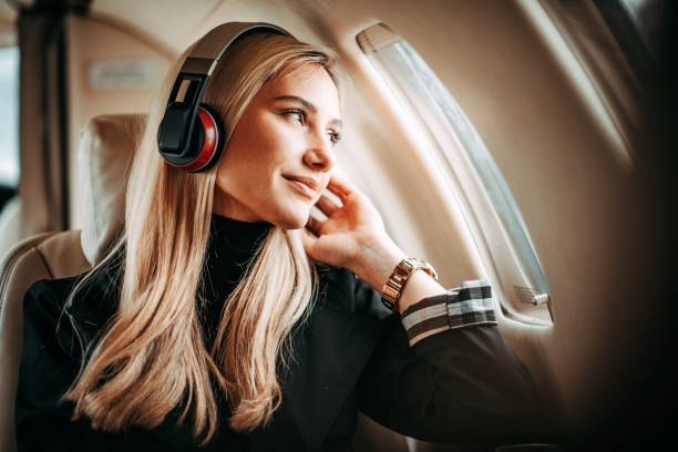 beautiful young woman listening to music through the headphones in a private jet - travel stock pictures, royalty-free photos & images