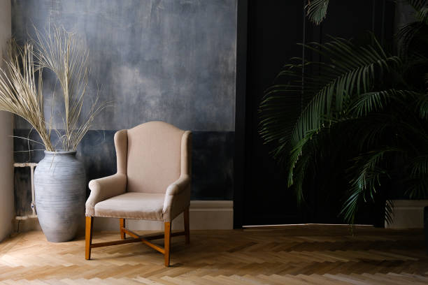 beige chair and a large vase near the window in the hall, next to a palm tree near the door. - home decoration stock pictures, royalty-free photos & images