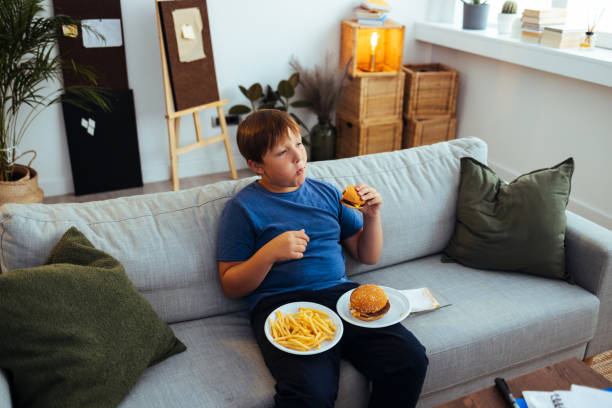übergewichtiger teenager isst junk-food-hamburger - junk food stock-fotos und bilder