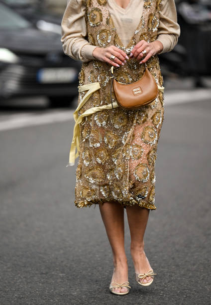 Bettina Looney is seen wearing a tan and gold sheer Miu Miu dress with brown Miu Miu bag outside the Miu Miu show during the Womenswear Fall/Winter...