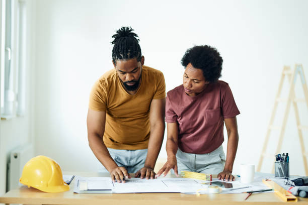 black couple examining blueprints during home renovation process. - home decoration stock pictures, royalty-free photos & images