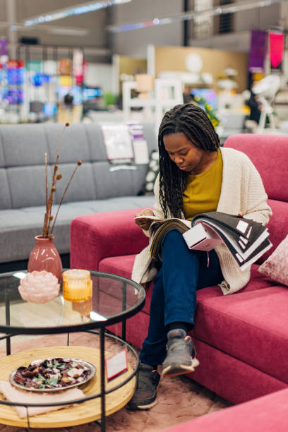 black woman chooses color and material for her new sofa bed while sitting in a department store looking at samples of materials and colors - home decoration stock pictures, royalty-free photos & images