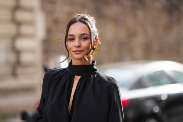 Blanca Arimany wears gold earrings, black long sleeve high neck shirt, outside Nina Ricci, during the Paris Fashion week Women's Fall/Winter...