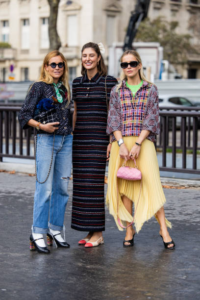 Blanca Miro Scrimieri wears denim jeans, black jacket, bag Maria de la Orden wears striped dress outside Chanel & Monica Anoz wears yellow pleated...