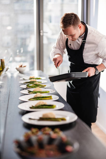 blonde caucasian male private chef plating dishes for a dinner party at a fancy apartment - food stock pictures, royalty-free photos & images