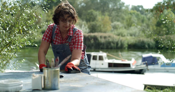 boat diy restoration. scraping off old blue paint from rusted metal surface - garden decoration stock pictures, royalty-free photos & images