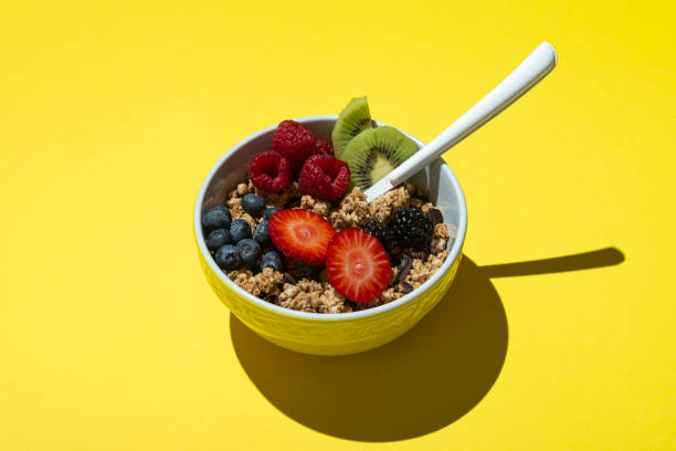 bowl with muesli ,chocolate and fruits on on yellow background - food stock pictures, royalty-free photos & images