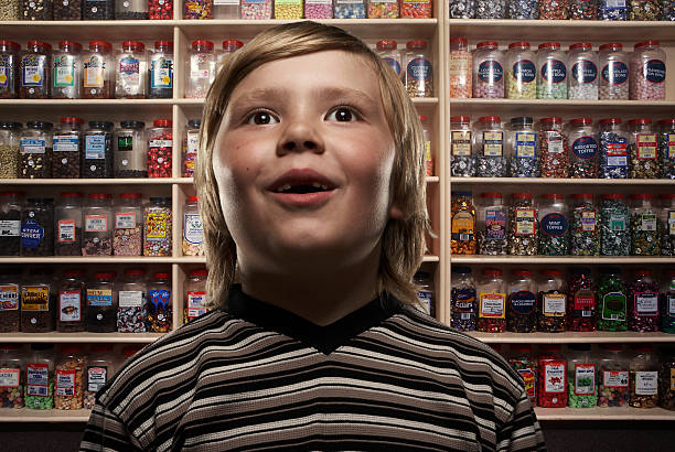 boy (6-8) in sweetshop, close-up (digital composite) - junk food stock pictures, royalty-free photos & images